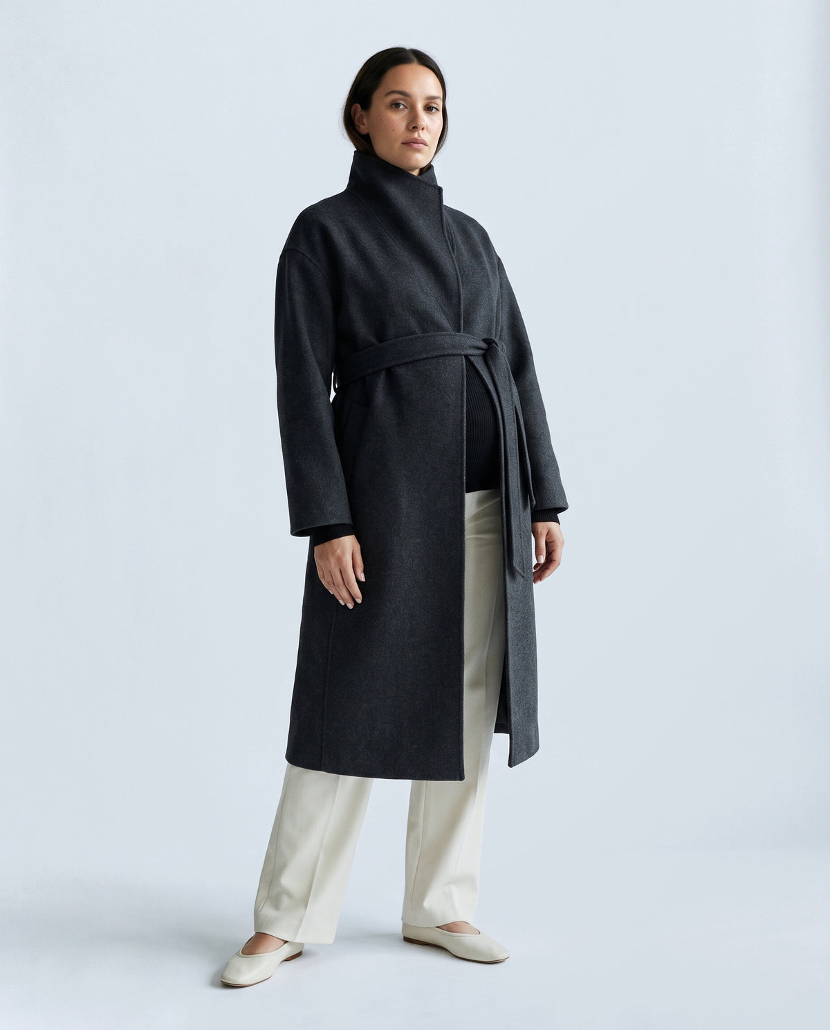 The Belted Stand-Collar Coat in Charcoal, closed over the bump